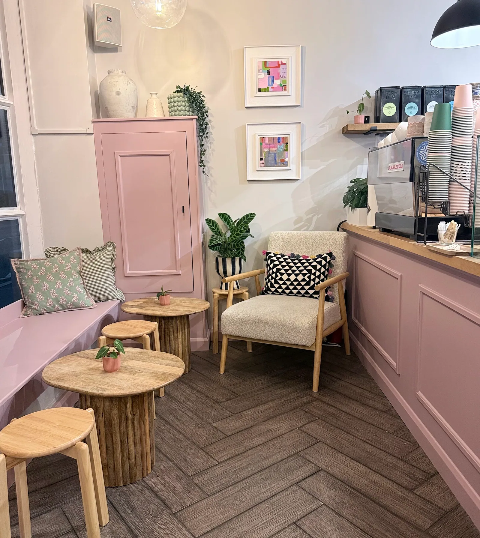 A cosy corner at Arlo, with pink panelling, a cream armchair, plants and the coffee counter